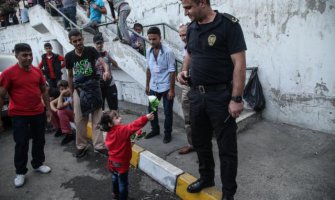 Djevojčica nudi cvijet policajcu kako bi njena porodica prešla granicu