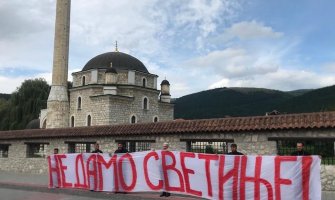 Krivokapić i sveštenici ispred Husein-pašine džamije sa transparentom 